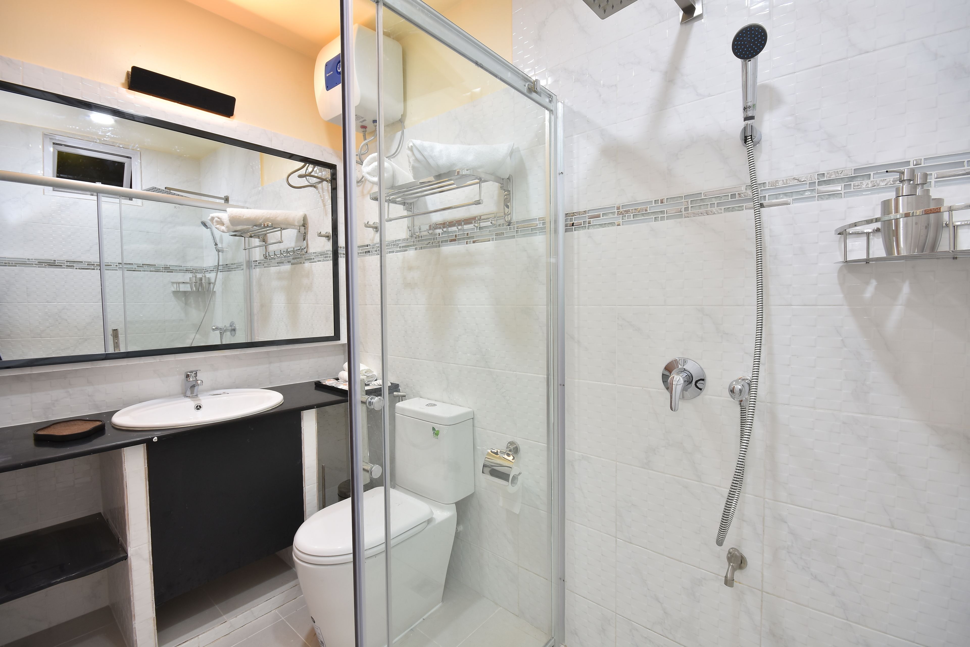 Un baño moderno con cabina de ducha de vidrio, un lavabo blanco y un inodoro.