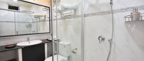 Un baño moderno con cabina de ducha de vidrio, un lavabo blanco y un inodoro.