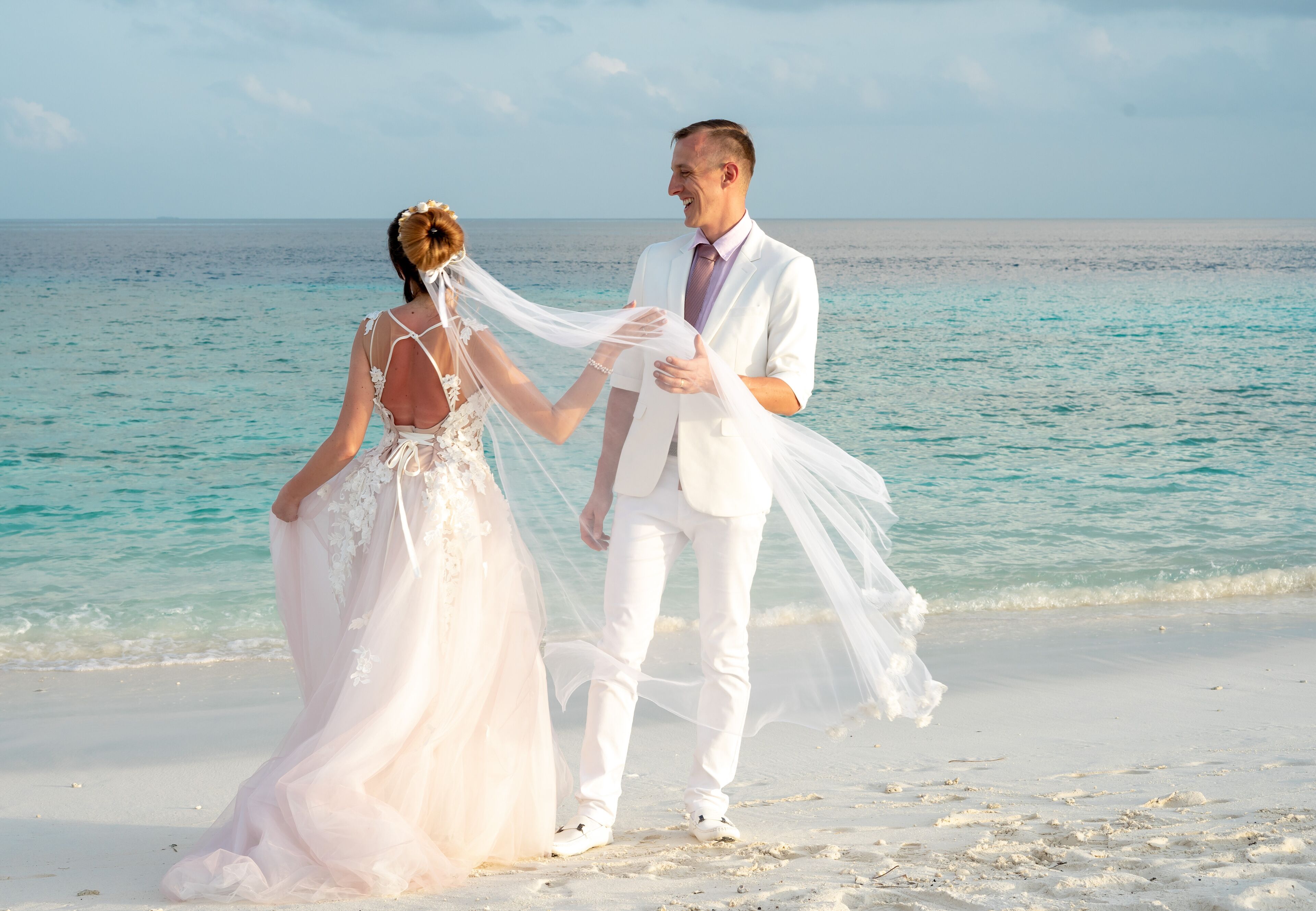A couple on a beach with the ocean in the background.