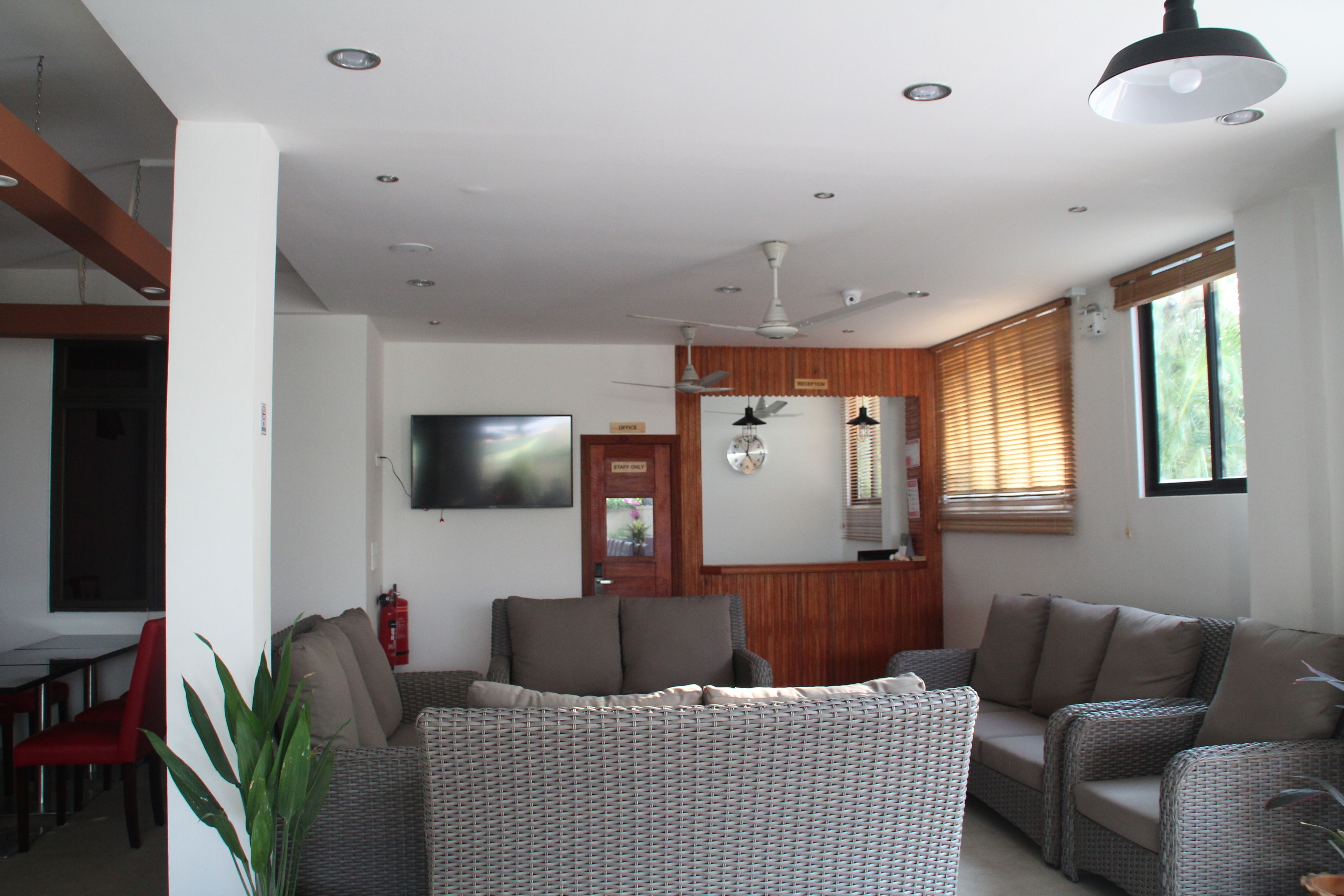 A modern living room with a sofa set, a flat-screen TV, and a ceiling fan.