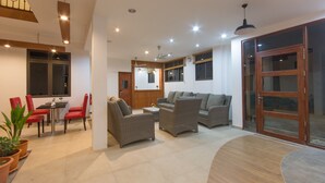 A spacious living area with a sofa, two armchairs, a dining table with chairs, and a sliding glass door.