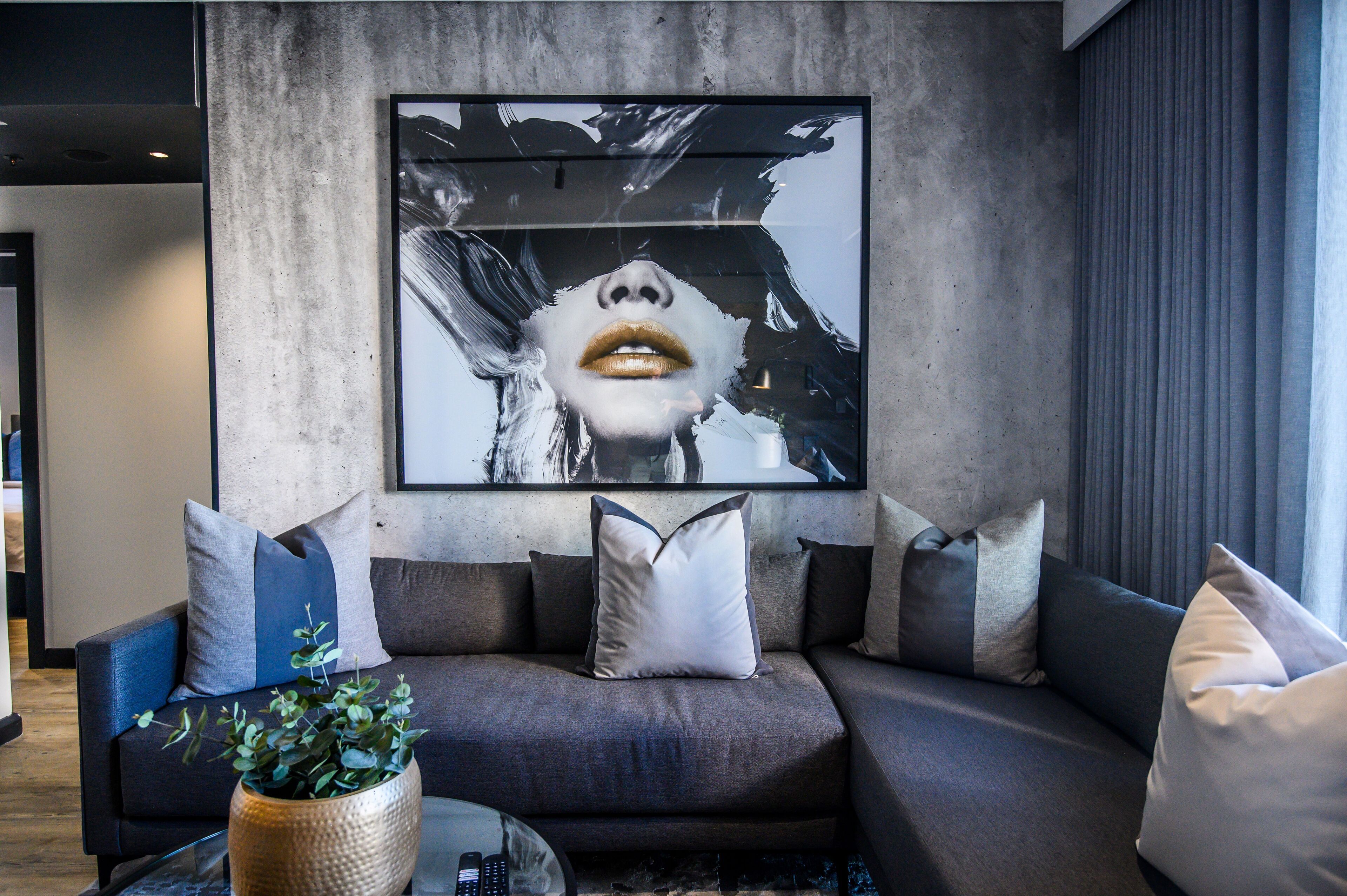 A modern living room with a grey sofa, a coffee table, and a large abstract painting on the wall.