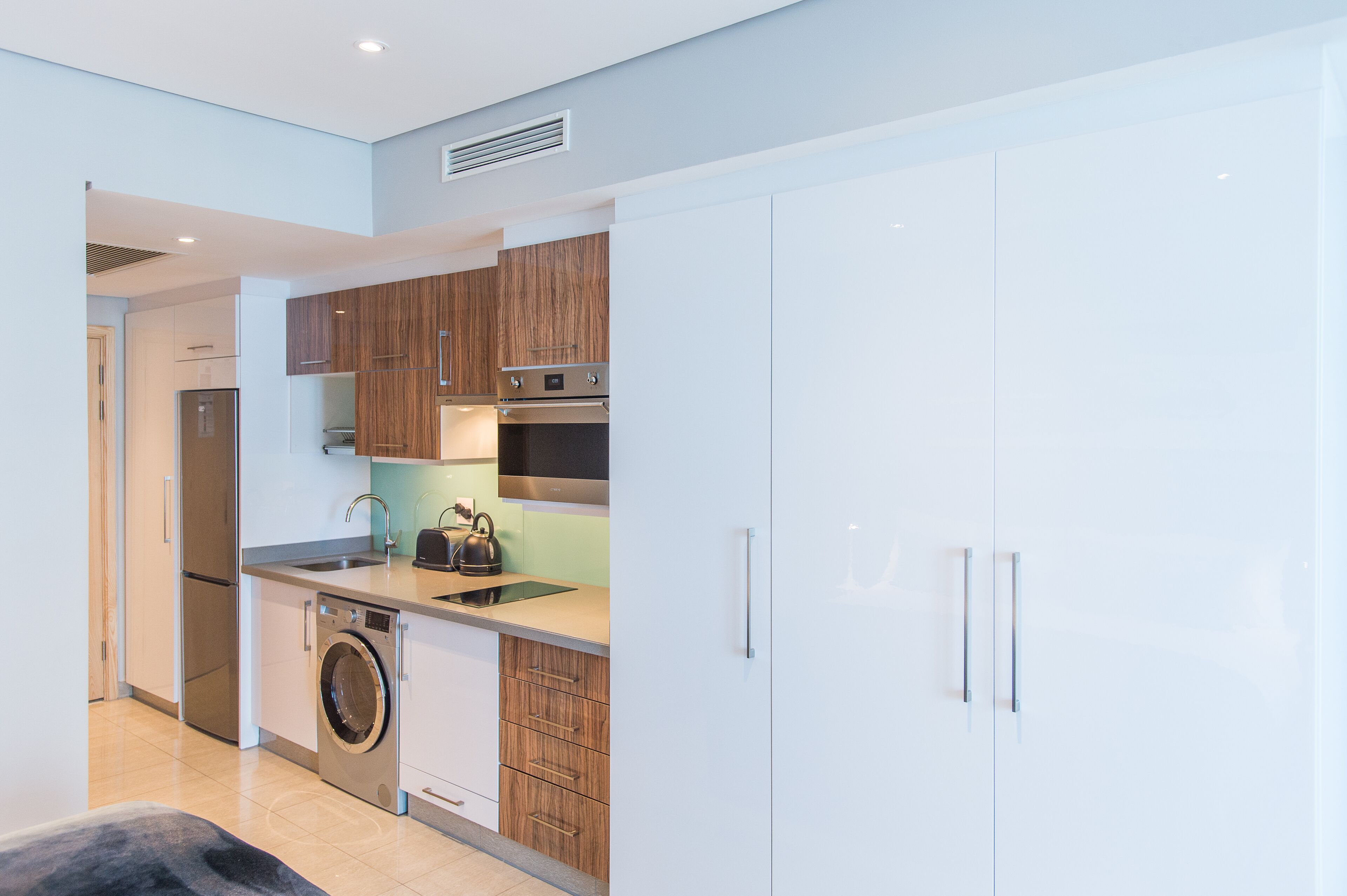 A modern kitchen with stainless steel appliances, wooden cabinets, and a built-in washing machine.