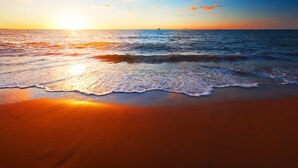 Une plage avec des vagues et un coucher de soleil.
