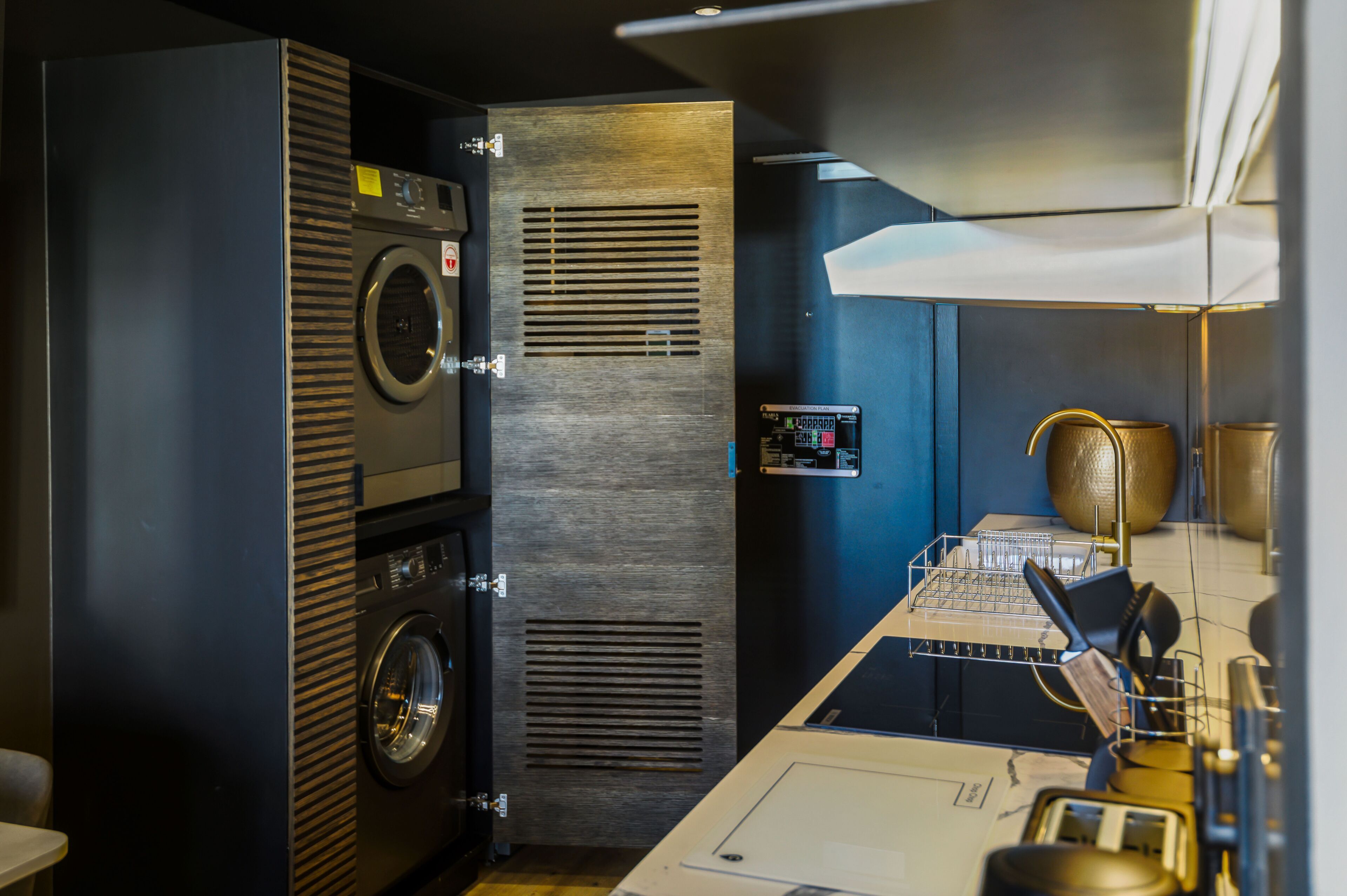 A compact laundry area with a washing machine and dryer, a control panel, and a drying rack.