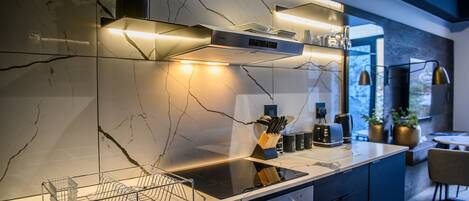 Una cocina moderna con encimera elegante, estufa integrada e iluminación bajo los armarios.