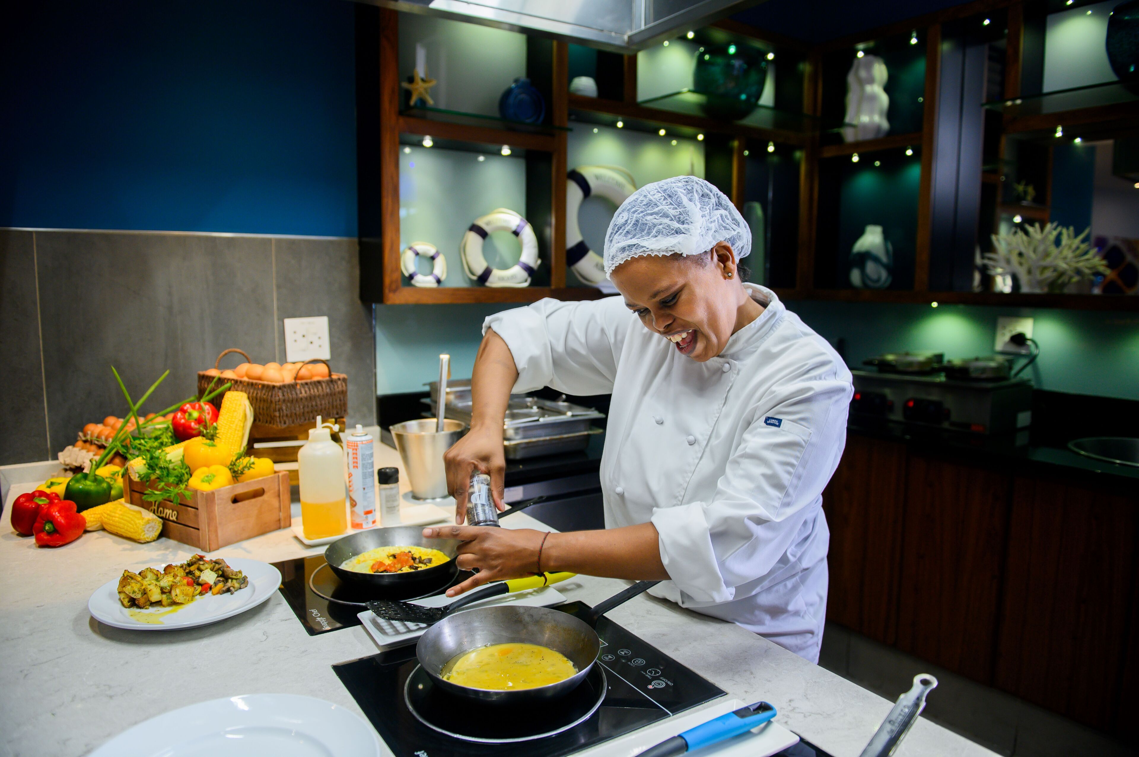 A chef in a kitchen preparing food with vegetables and a pan on an induction cooktop.