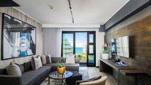 Un salon moderne avec un canapé gris, une table basse et un téléviseur fixé à un mur en bois.