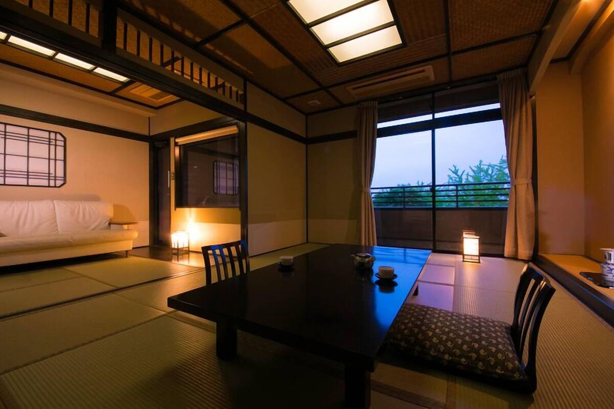 Une pièce de style japonais traditionnel, avec un sol recouvert de tatamis, une table basse, un canapé et une porte coulissante.