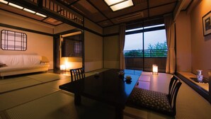 Ett traditionellt japanskt rum med tatamimattor på golvet, ett lågt bord, en soffa och utsikt genom en skjutdörr.