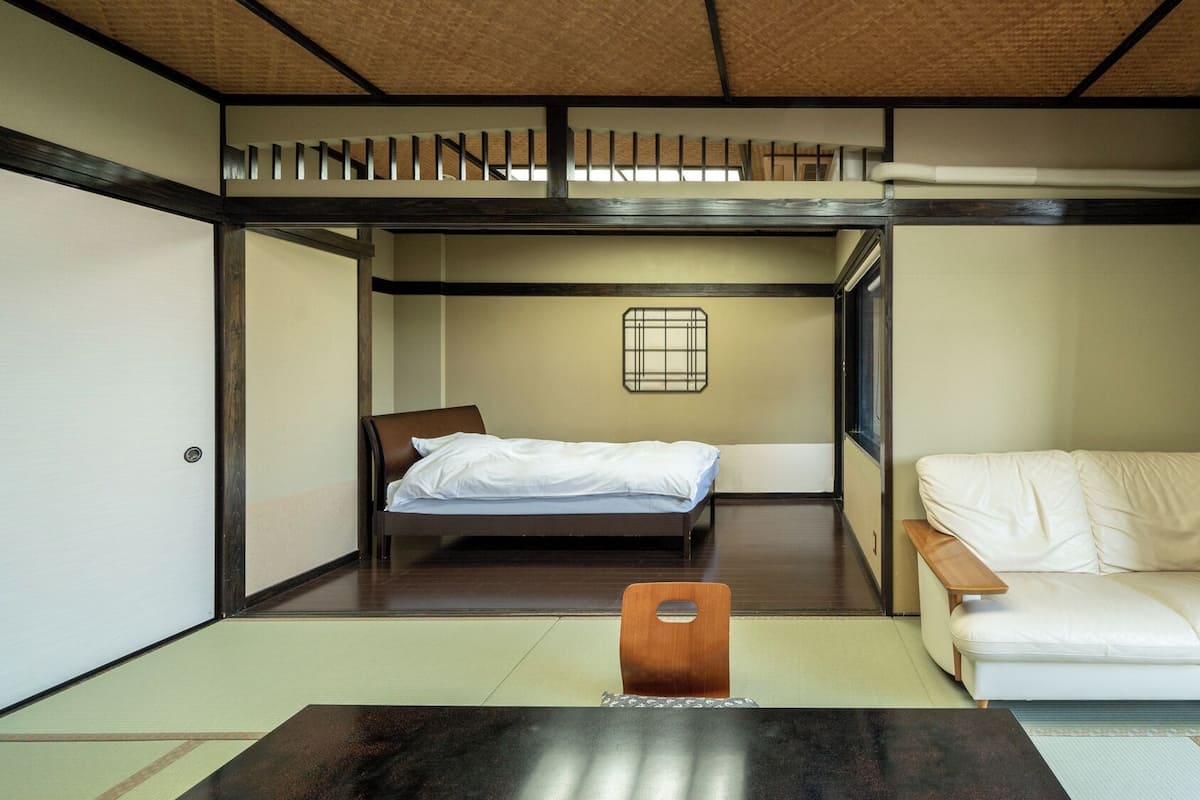 Une pièce de style japonais traditionnel, avec un sol recouvert de tatamis, un lit bas, un canapé et une petite table.