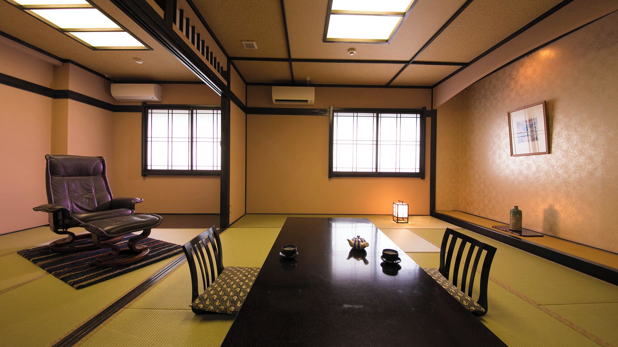 Una habitación tradicional de tatami con una mesa baja, esteras de tatami, un sillón de cuero negro y una ventana con pantalla shoji.