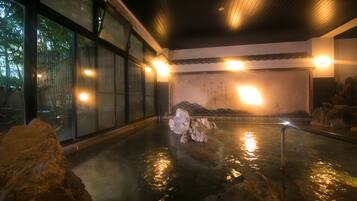 Relax in a serene hot spring bath surrounded by natural ambiance and smooth rocks.
