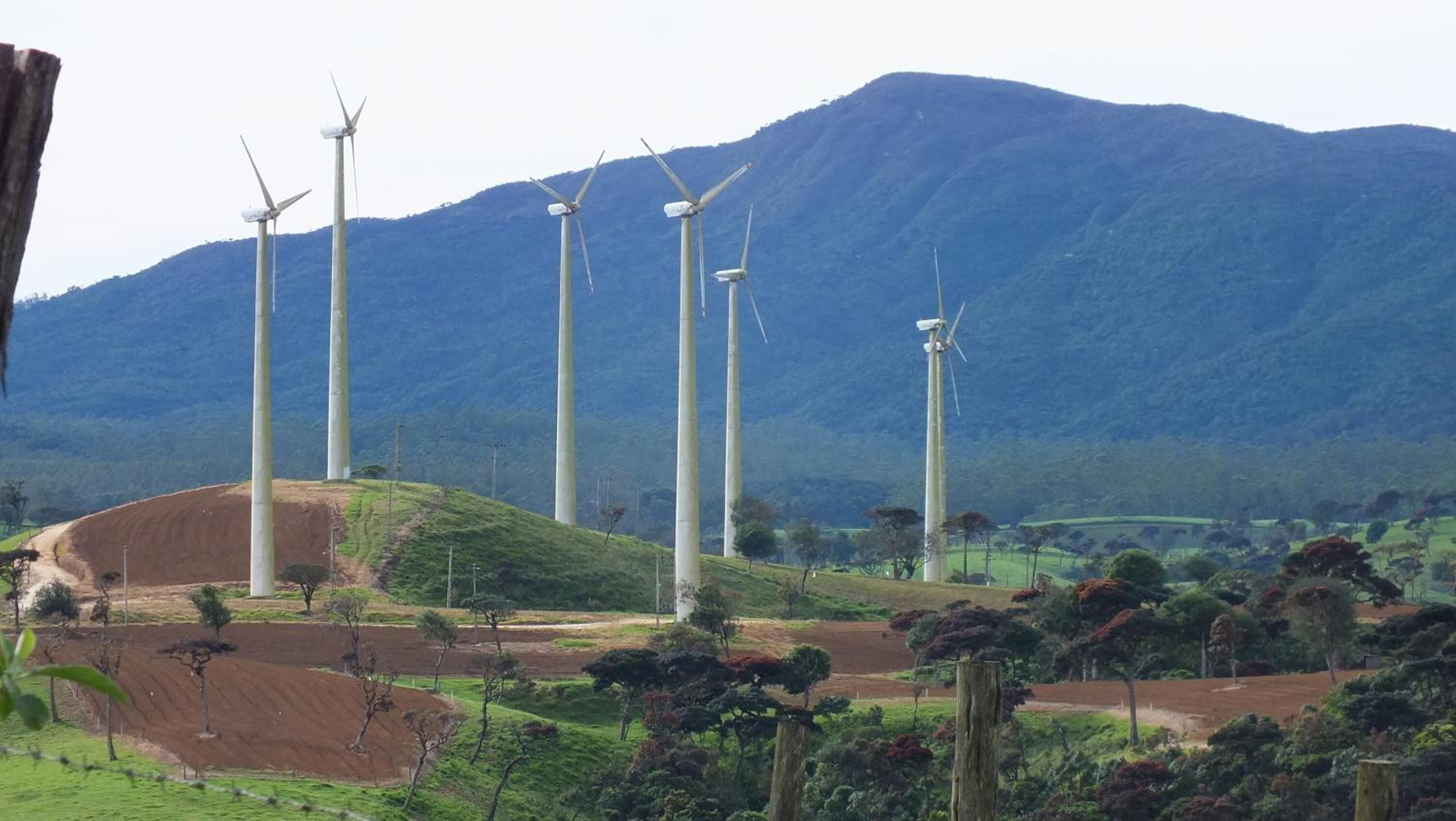 A wind farm with multiple wind turbines in a hilly landscape.