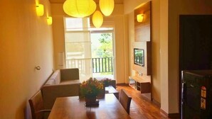 Un coin repas avec une table et des chaises en bois, un canapé et un téléviseur posé sur un meuble.