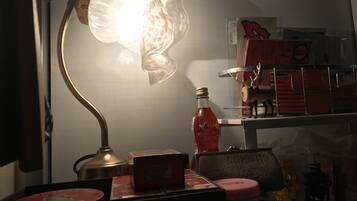 A desk with a lamp, a bottle, and various items on a shelf.