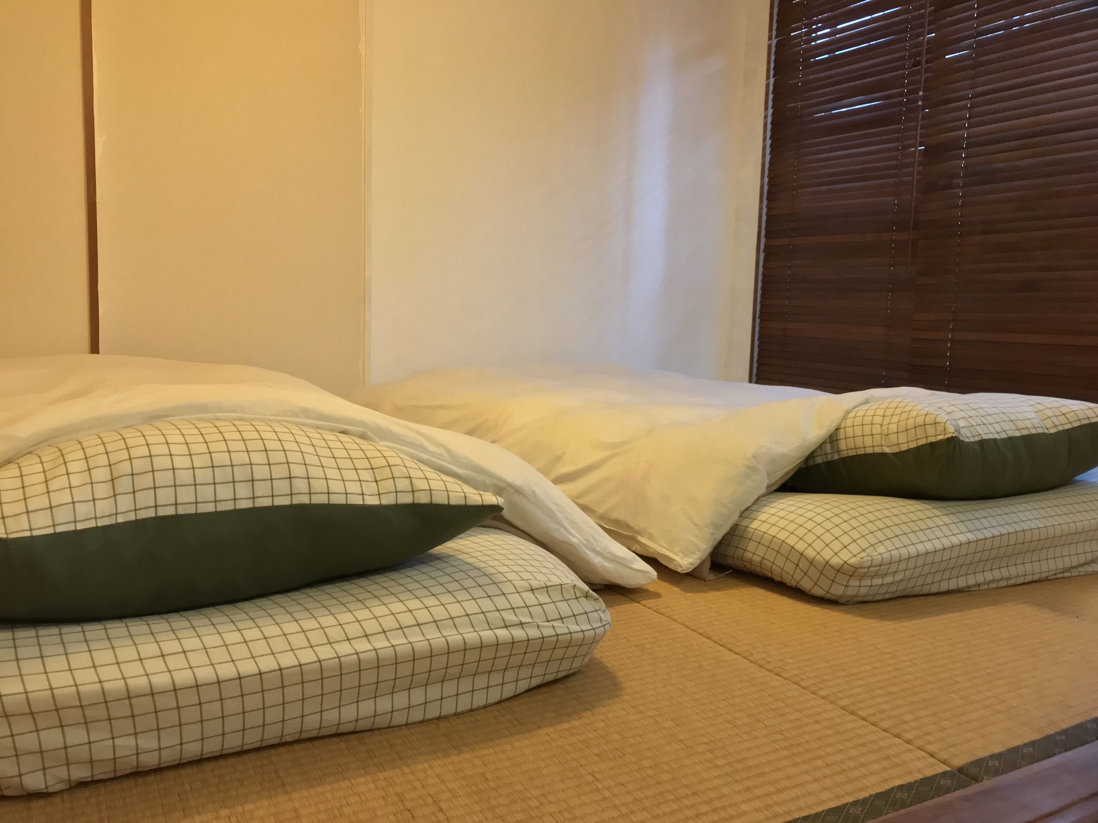 A room with a bed, pillows, and a window with blinds.