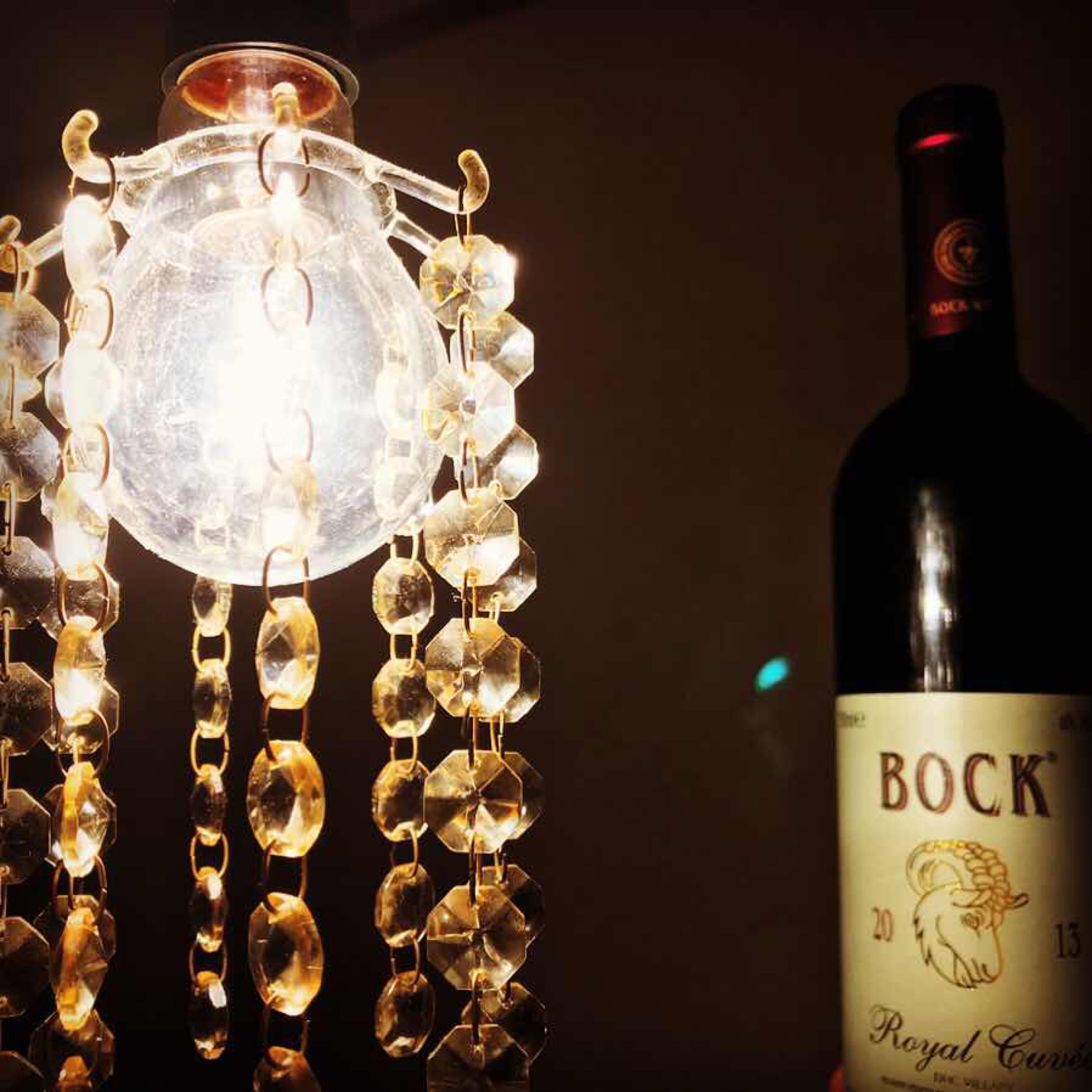 A bottle of Bock Royal Curves wine next to a decorative light fixture.