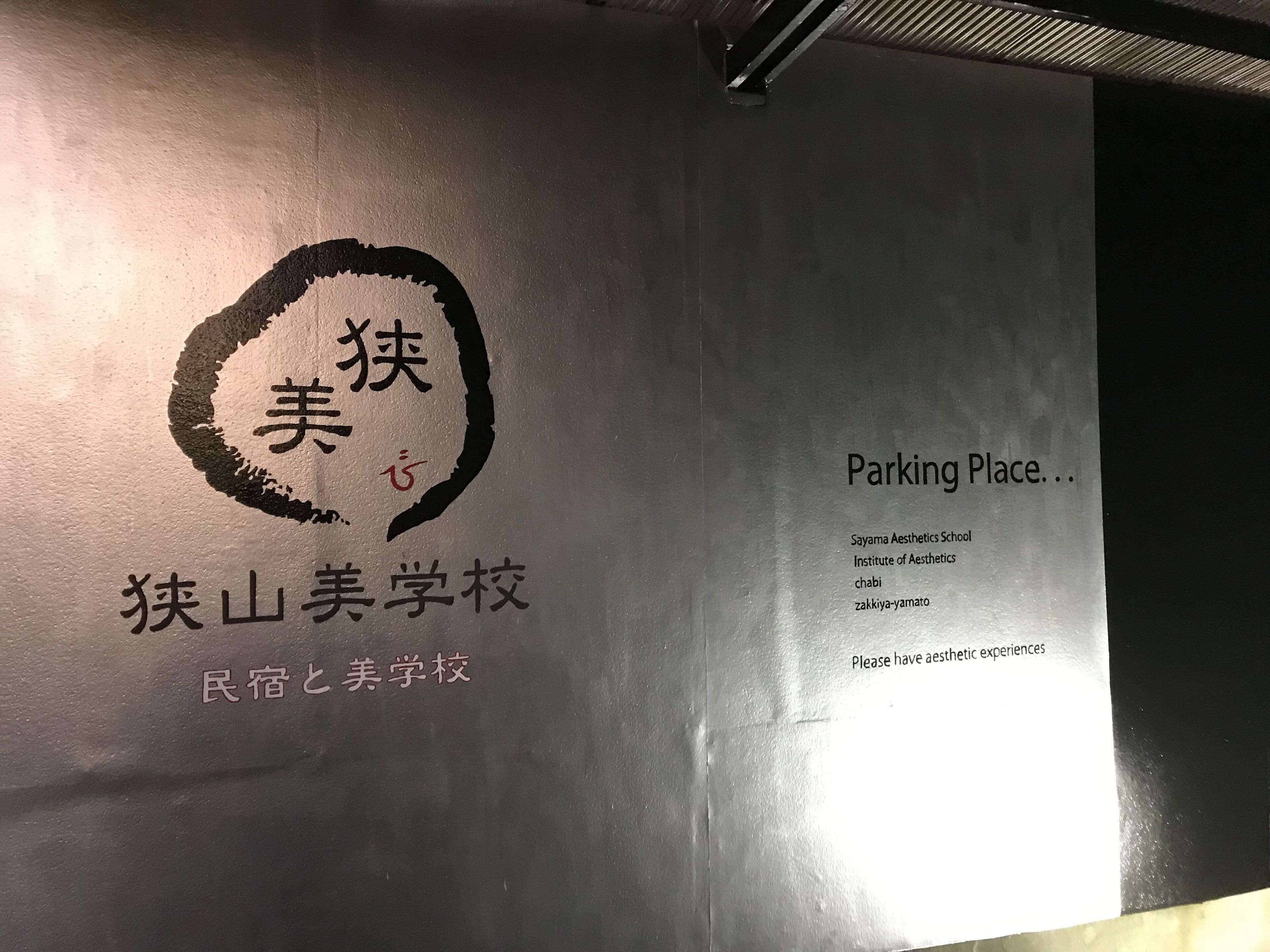 A wall with a logo and text indicating a school, including a parking sign.