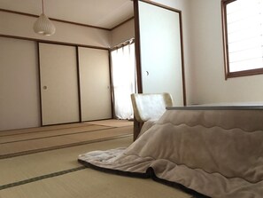 A traditional Japanese room with tatami flooring, a low table, and sliding doors. - Sayama Aesthetics School (Osakasayama)