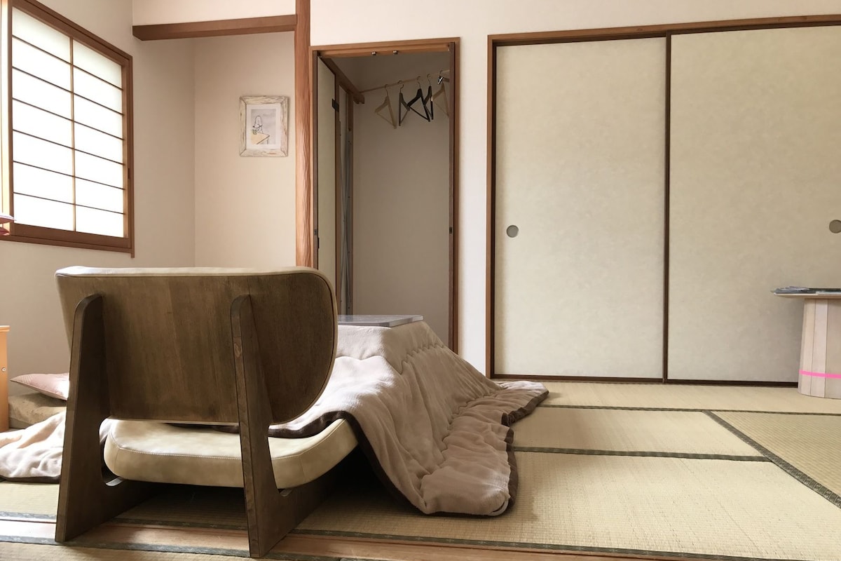 A tatami mat room with a traditional Japanese sliding door, a wooden chair, and a small table.