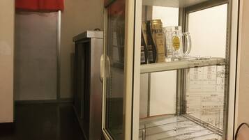 A vending machine with a Coca-Cola logo, containing a bottle and a glass.