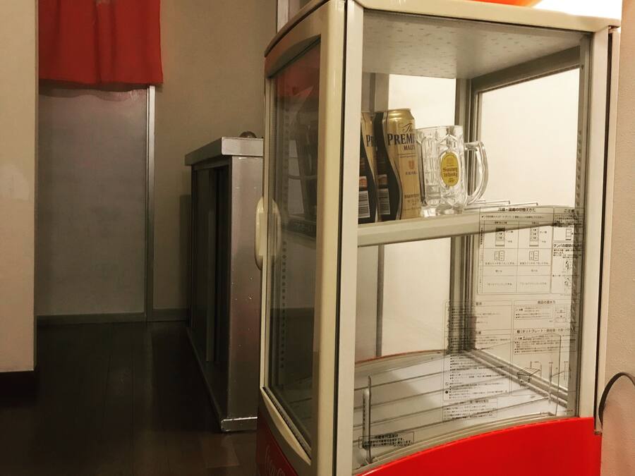 A vending machine with a Coca-Cola logo, containing a bottle and a glass.