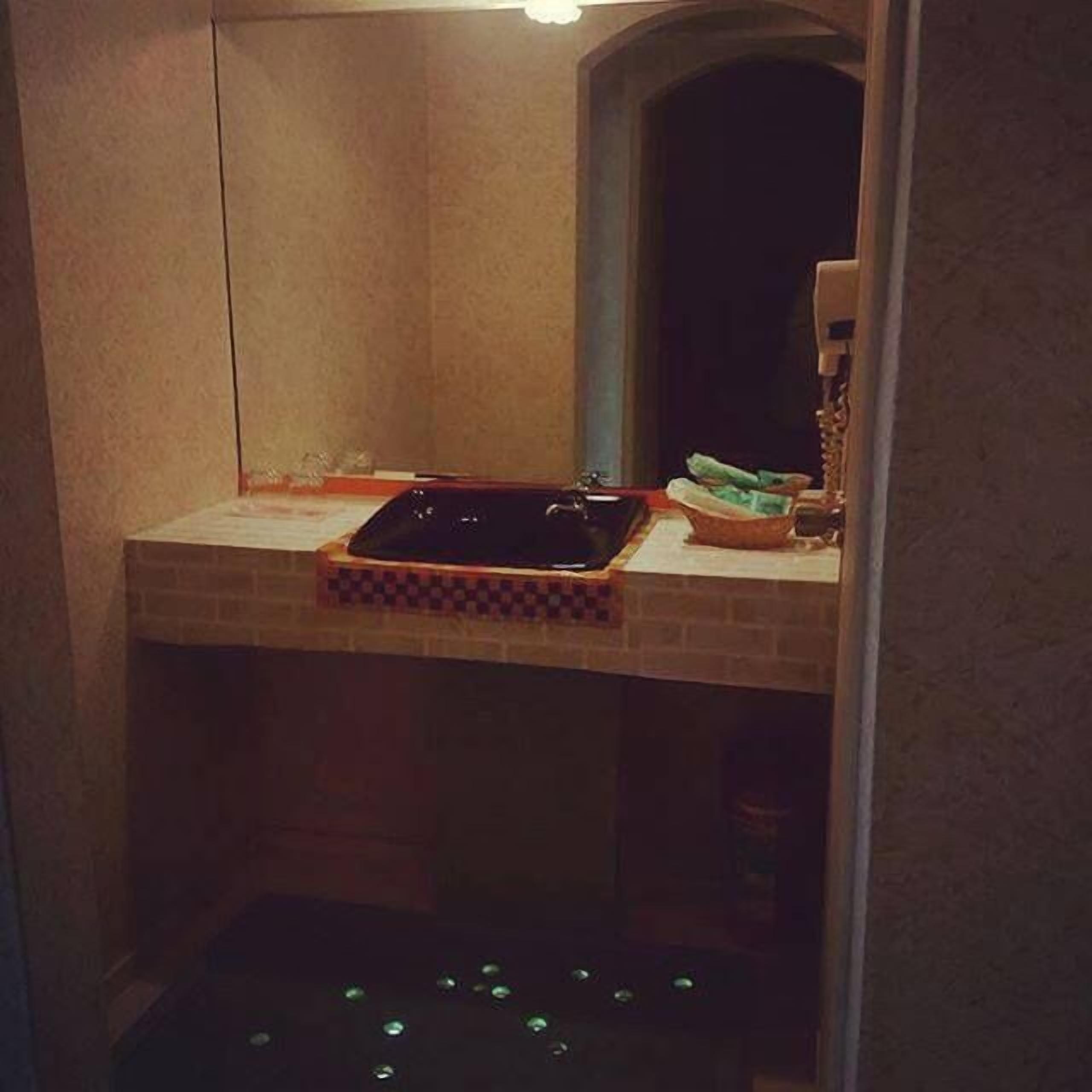 A small, dimly lit room with a tiled floor, a sink, and a mirror.