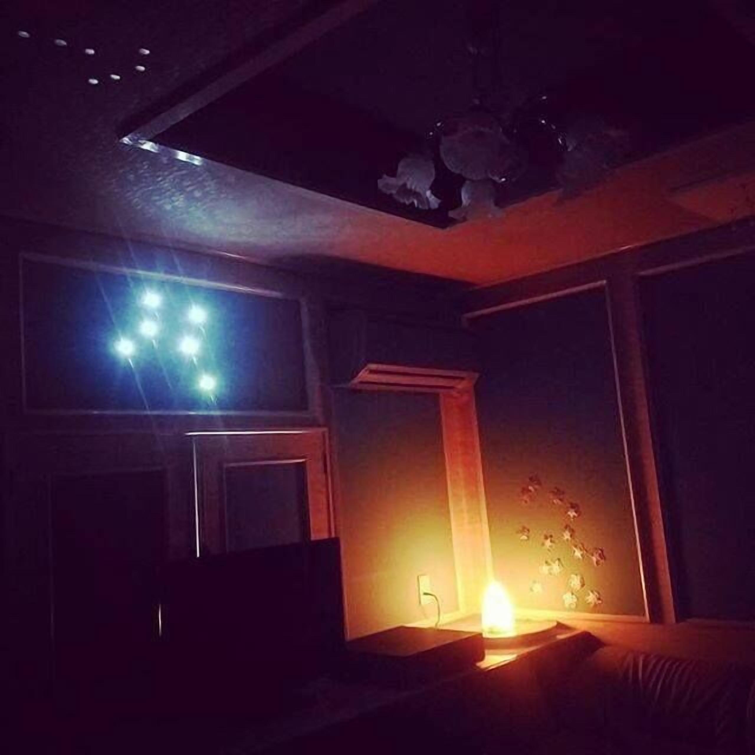 A dimly lit room with a bed, a desk, and a window.