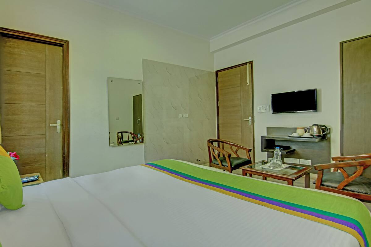 A hotel room with a bed, a desk, a chair, a television, and a wardrobe.