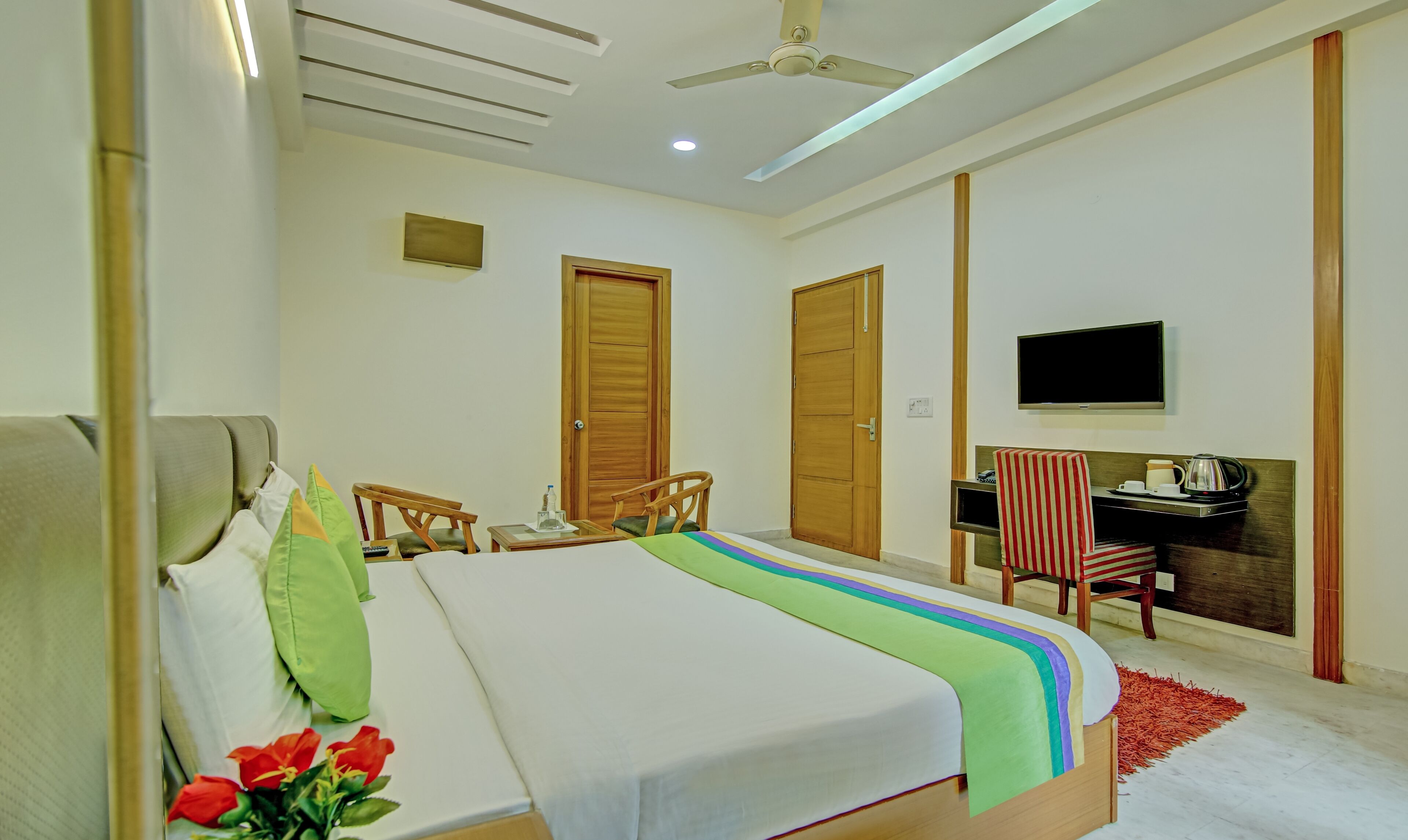 A bedroom with a bed, a desk, a chair, and a TV.