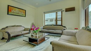 A living room with two sofas, a coffee table, and a painting on the wall. - Itsy Hotels Swastika Inn Sector 26 (Noida)