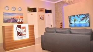 Una zona reception con una scrivania in legno con un logo, un divano grigio e orologi a parete.