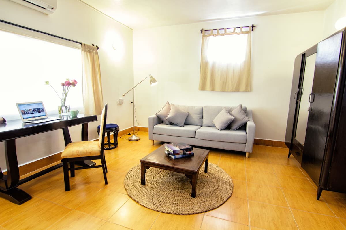 A living room with a sofa, a coffee table, a desk with a laptop, and a lamp.