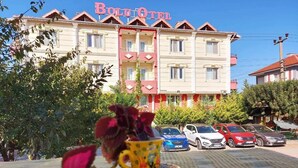 Un hôtel reconnaissable à son enseigne bien visible, doté de nombreux balcons et avec des voitures garées devant.