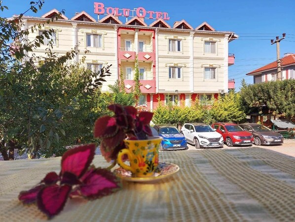 Un hotel con un letrero llamativo, varios balcones y coches estacionados al frente.