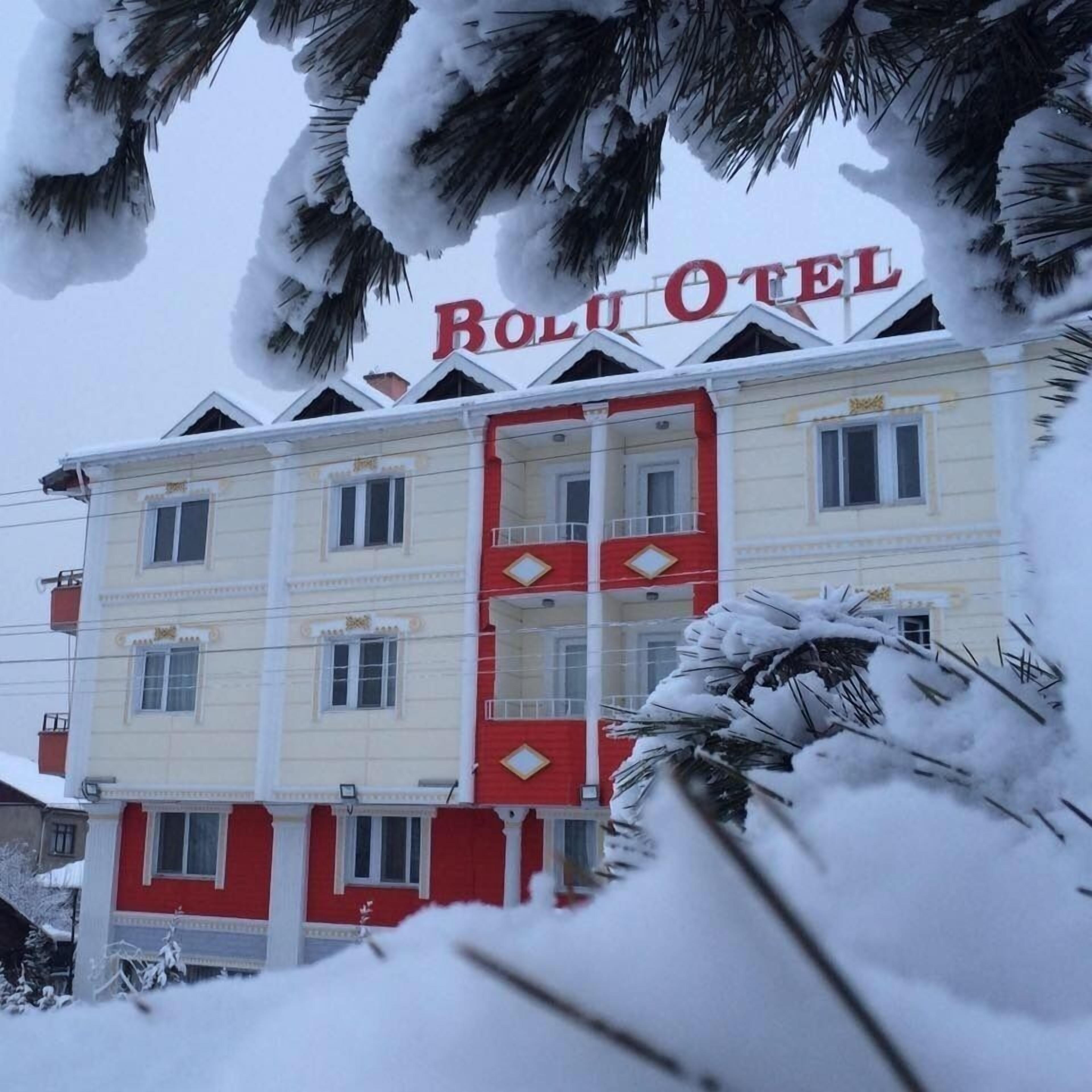 A hotel with a red and white facade, multiple windows, and balconies.