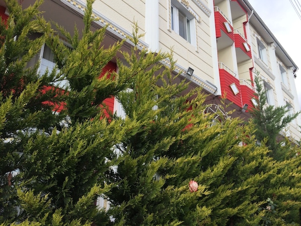 Un bâtiment à la façade rouge et blanche, doté de balcons et d’une fenêtre ornée d’un motif circulaire en métal.