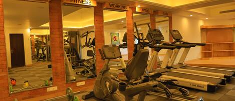 Une salle de sport équipée de tapis de course, de vélos d’appartement et d’appareils de musculation.