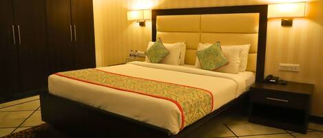 A hotel room with a large bed, bedside tables, a wardrobe, and wall-mounted lamps.