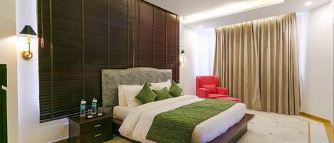 Un hotel moderno con una cama grande, una mesita de noche, una silla roja y vistas de la ciudad a través de la ventana.