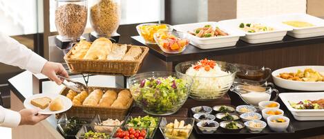 Un bufé con diversos alimentos, entre ellos pan, ensaladas y otros platos.
