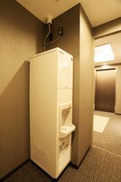Une chambre d’hôtel équipée d’un distributeur de glaçons blanc, d’un climatiseur mural et d’une porte donnant accès à un ascenseur.