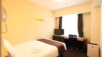 Habitación de hotel con cama, escritorio con computadora, televisor, teléfono y refrigerador pequeño.