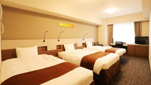 Une chambre d’hôtel avec trois lits, un bureau, une télévision et une fenêtre avec des rideaux.