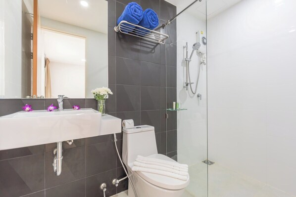 A modern bathroom with a white sink, a glass shower enclosure, and a toilet.