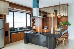 Una cocina moderna con una isla central, armarios de madera y un ventanal grande.