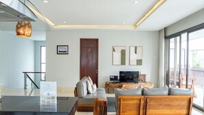 A modern living room with a sofa, TV, and a wooden coffee table. - Mentari Hill View 8 BR heated pool and movie room (Bandung)