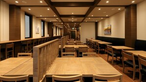 A restaurant with wooden tables and chairs, high ceilings with recessed lighting, and a view of the cityscape through the windows. - Hotel Route Inn Toyohashi Ekimae (Toyohashi)