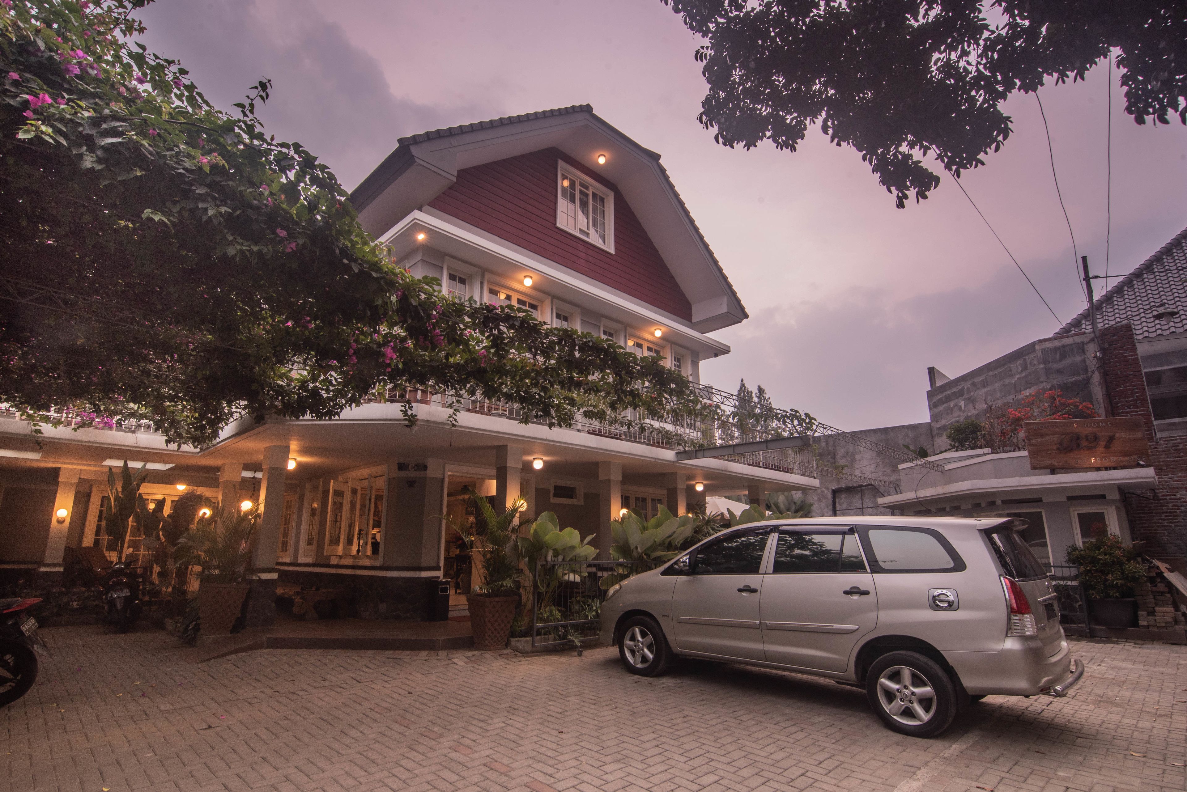 A two-story building with a red roof and a balcony. There is a car parked in front.